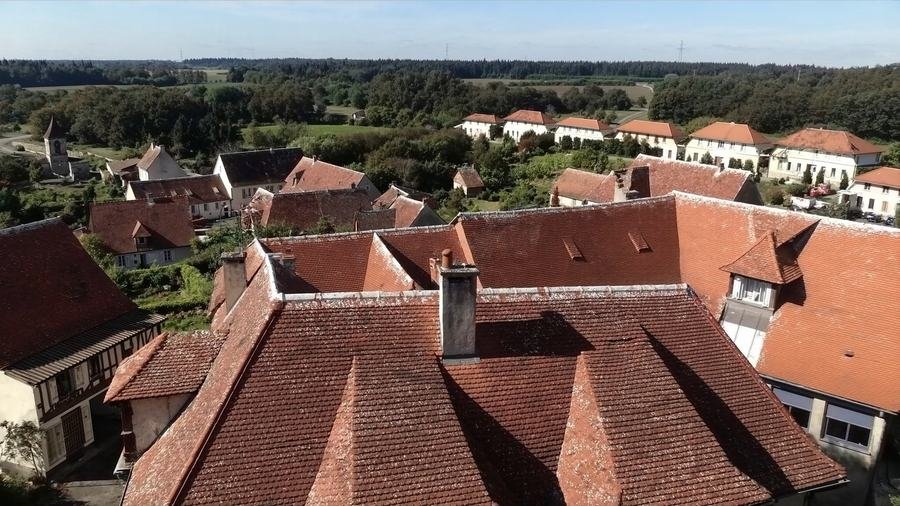 Vue aérienne des toits d'un village d'Île-de-France, tuiles ocre rouge et toits d'ardoise