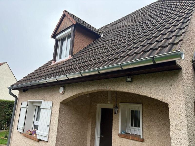Façade d'entrée d'un pavillon avec gouttière, descente et lucarne en toiture